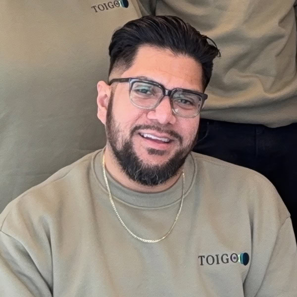 Entrepreneur wearing Toigo Foundation branded sweatshirt, smiling confidently, promoting leadership and innovation programs for diverse entrepreneurs.
