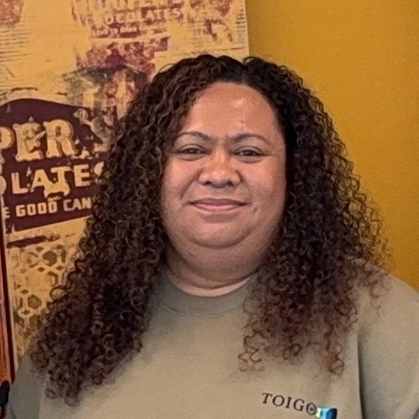 Toigo Foundation representative with curly hair smiling at an indoor event promoting leadership and empowerment in diversity.